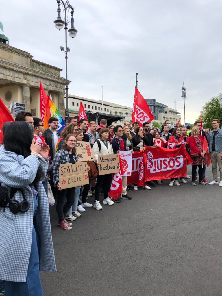Gruppenbild der Jusos mit Flaggen vor dem Brandenburger Tor am Arbeitskampftag 2022
